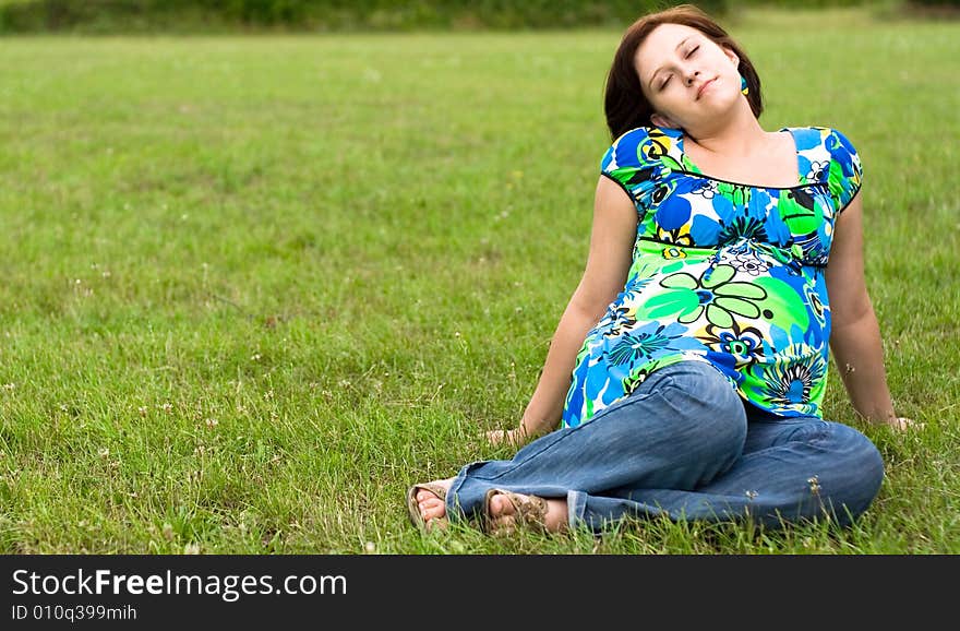 Pregnant woman relaxing on grass. Pregnant woman relaxing on grass