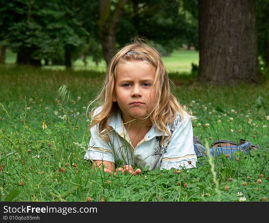 Boy with long blond hair is lying in the grass. Boy with long blond hair is lying in the grass