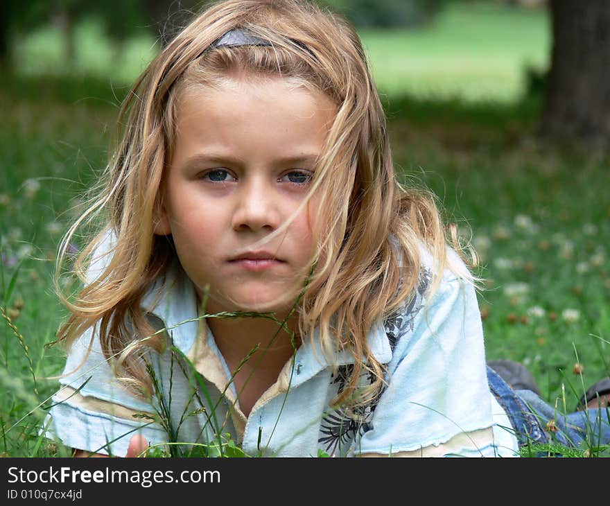 Boy with long blond hair is lying in the grass. Boy with long blond hair is lying in the grass