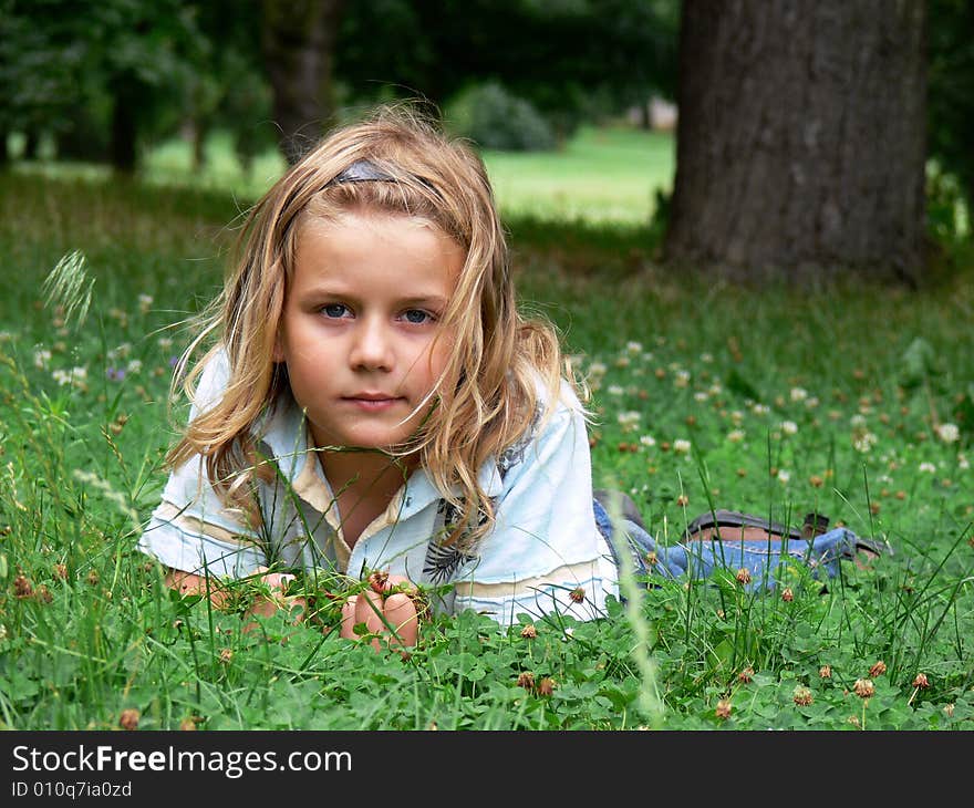 Boy with long blond hair is lying in the grass. Boy with long blond hair is lying in the grass