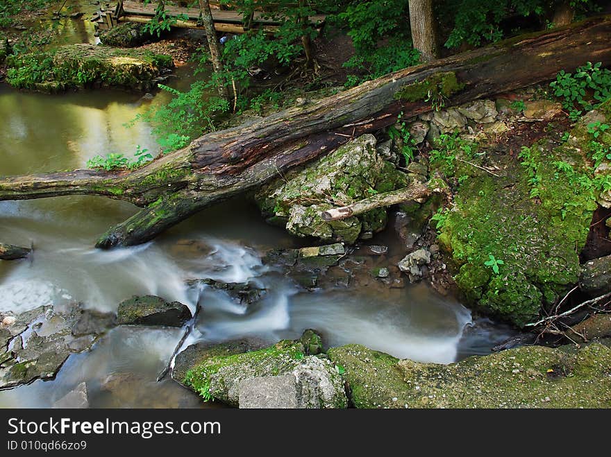 This is an area of a dam on a small creek. The water has broke through on one side.The view is taken from the top of the dam looking down.