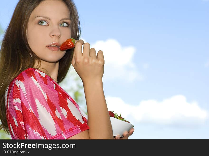 Pretty girl relaxing on green grass and eat red fr