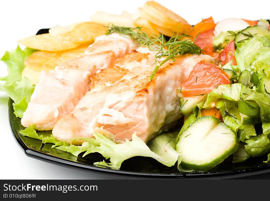 Stake from a salmon with vegetables on a plate. Closeup.