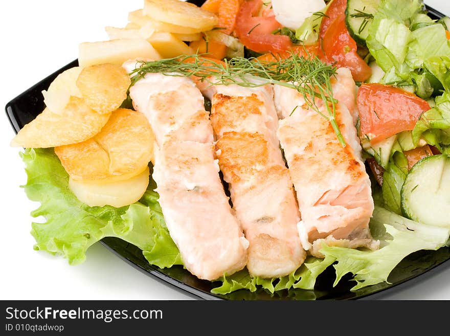 Stake from a salmon with vegetables on a plate. Closeup.