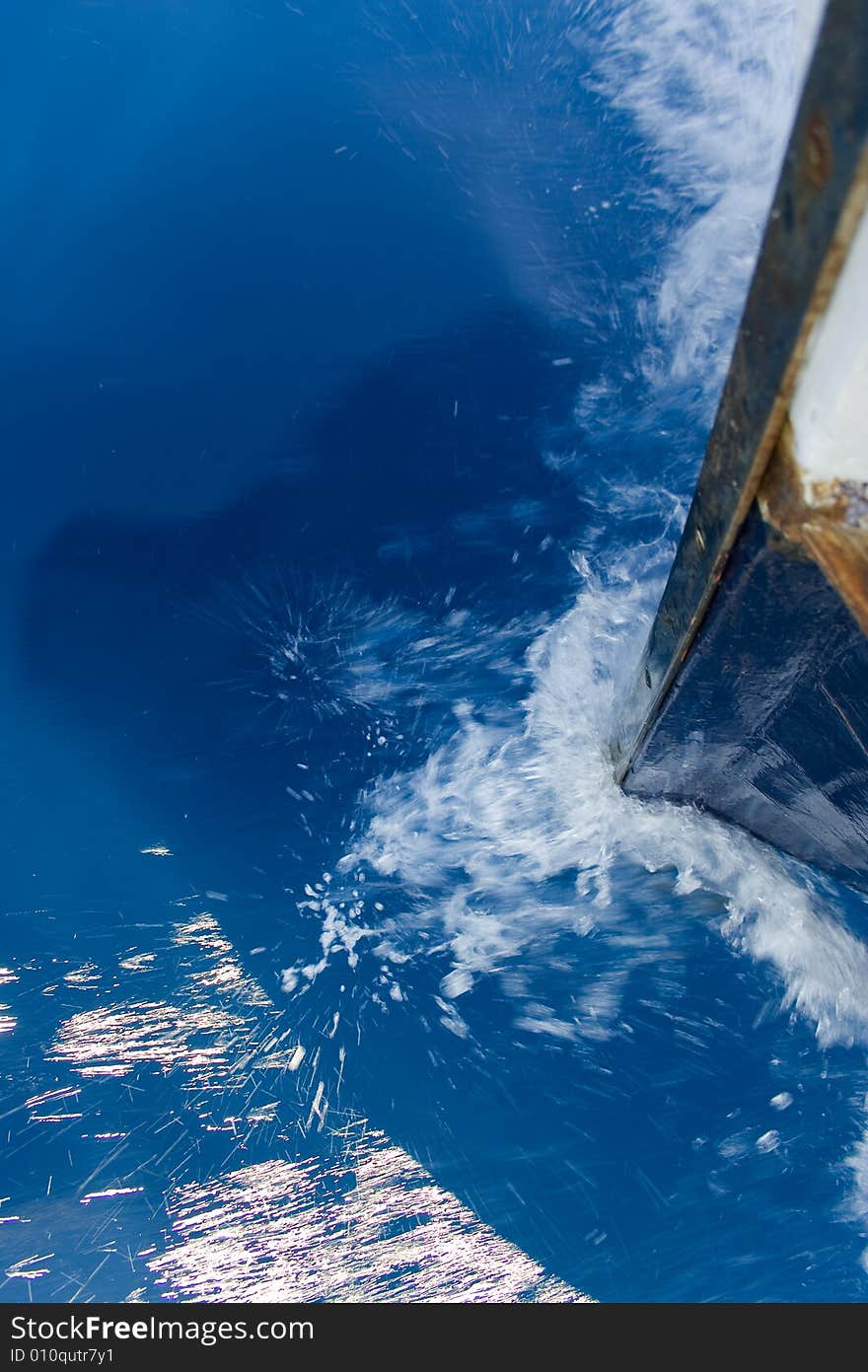 A closeup view of the bow and splashing water of the bow wave from an old fishing boat as it moves through water. A closeup view of the bow and splashing water of the bow wave from an old fishing boat as it moves through water.