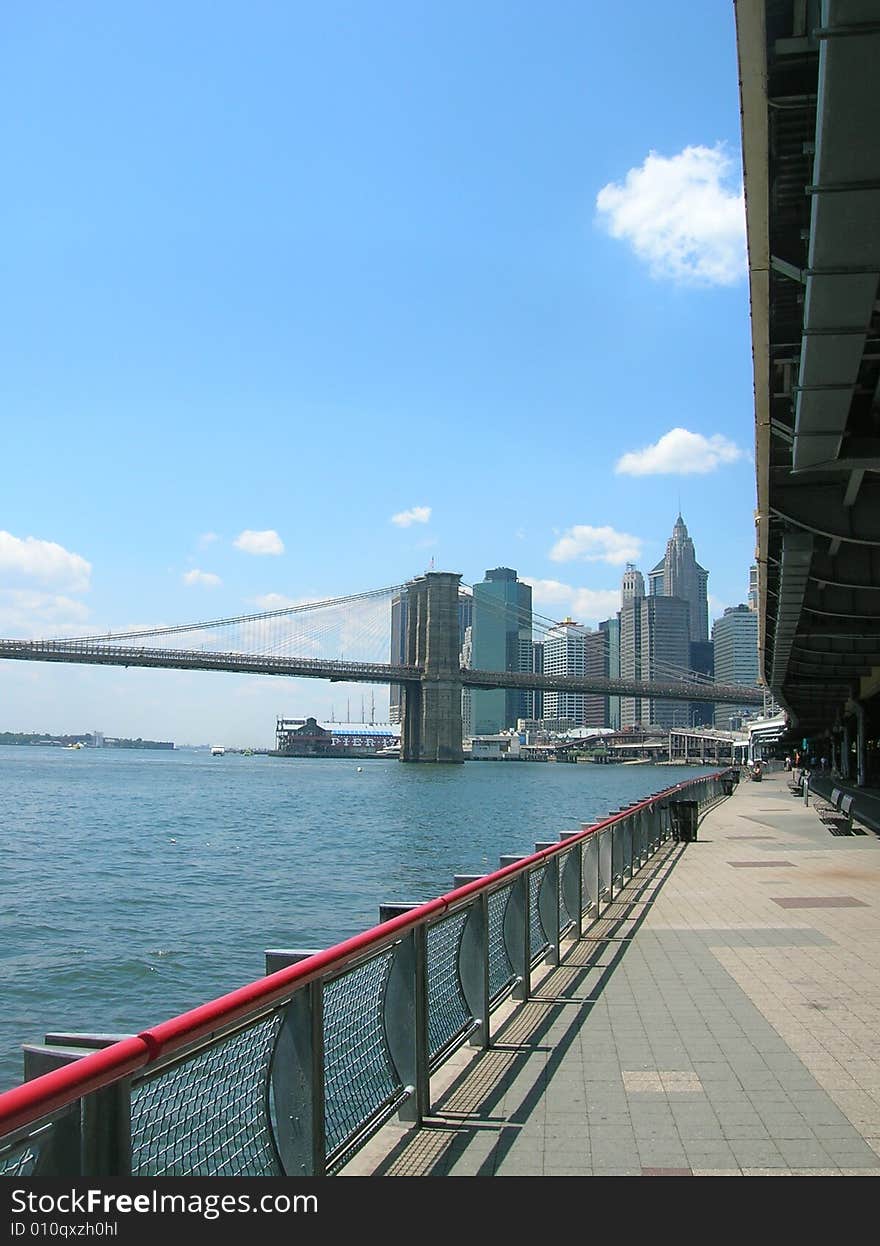 Path along New York's East River. Brooklyn Bridge in the distance.