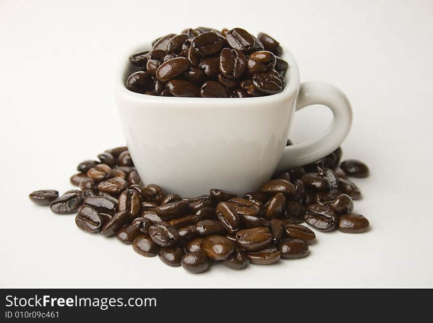 Whole coffee beans in a white cup. Whole coffee beans in a white cup.