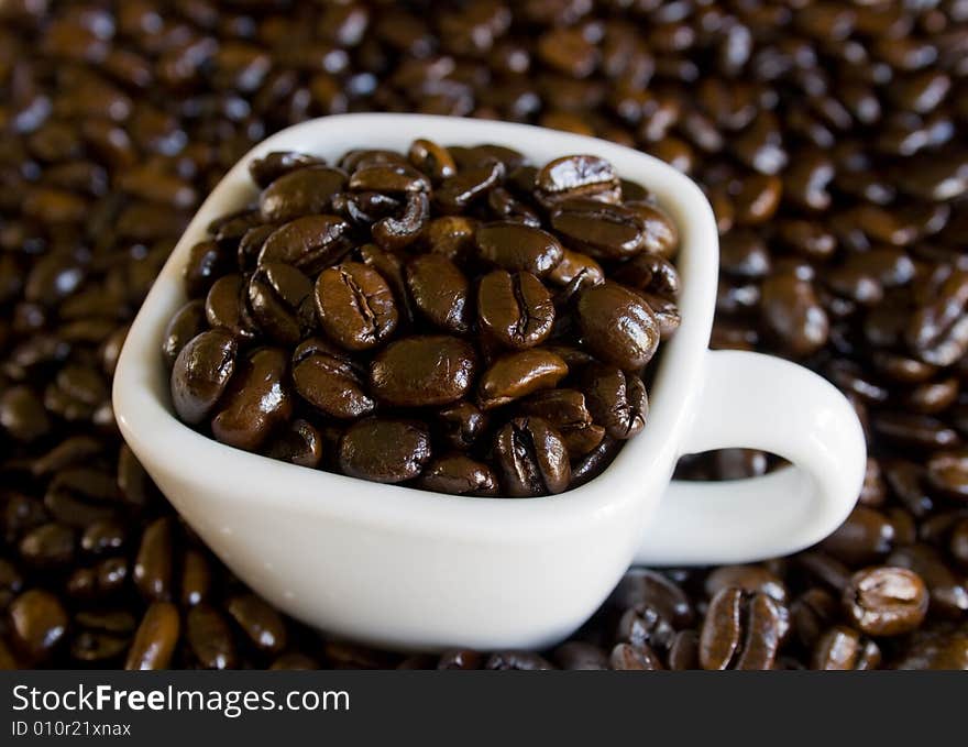 Whole coffee beans in a white cup. Whole coffee beans in a white cup.