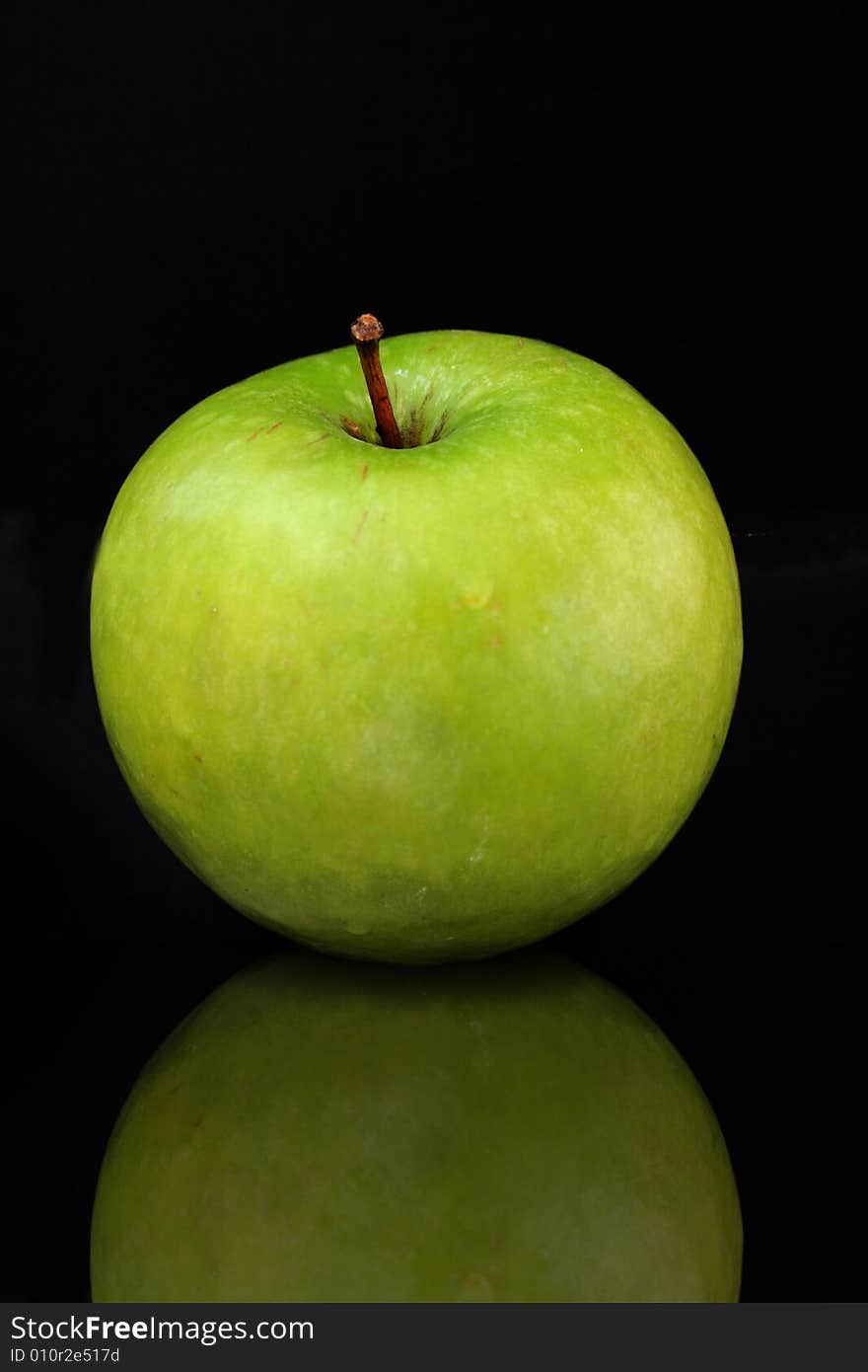 Green apple isolated on a black bacground with a reflection.