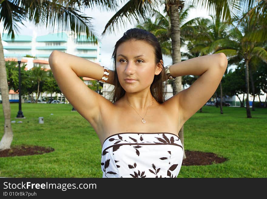 Woman sitting in a park pulling back her hair. Woman sitting in a park pulling back her hair.