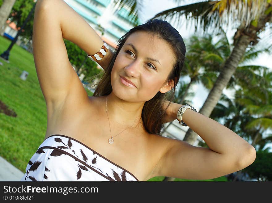 Woman sitting in a park pulling back her hair. Woman sitting in a park pulling back her hair.