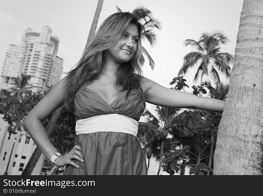 Woman smiling with her hand extended towards a tree.