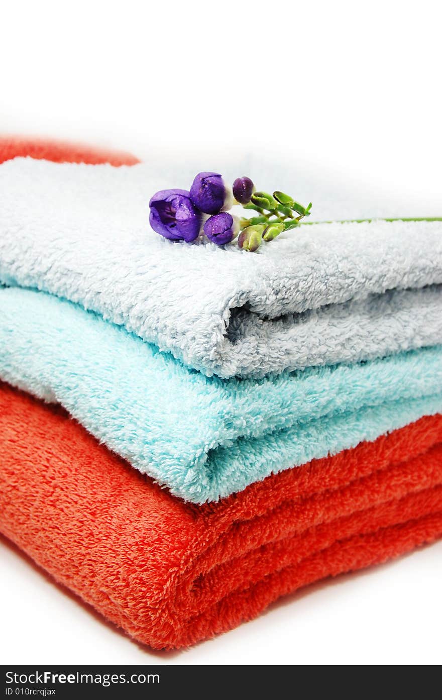 Towels in pile and violet flower. Towels in pile and violet flower