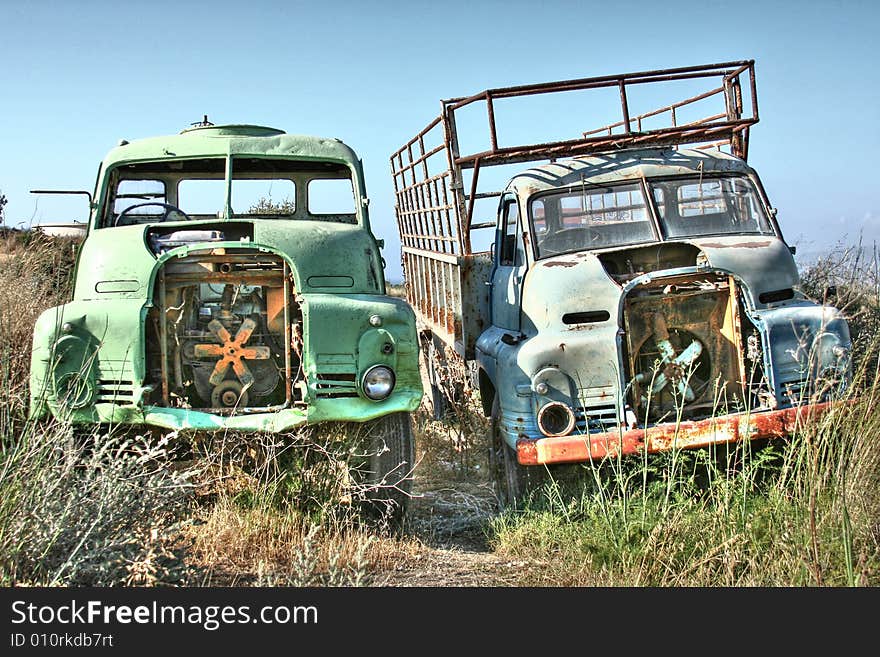 Two abandoned trucks rusting away at the edge of a field