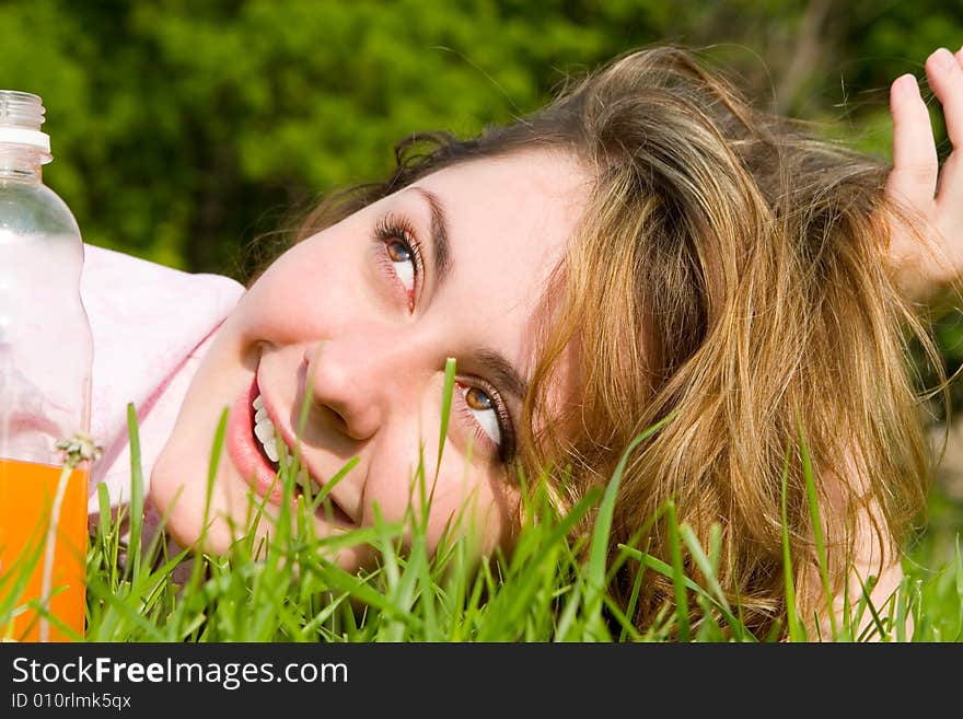 Pretty woman drinking juice on the summer glade