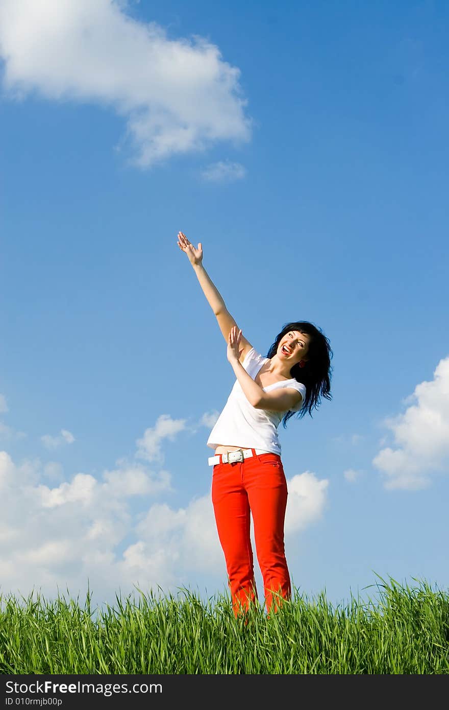 Young woman on a green meadow and show something