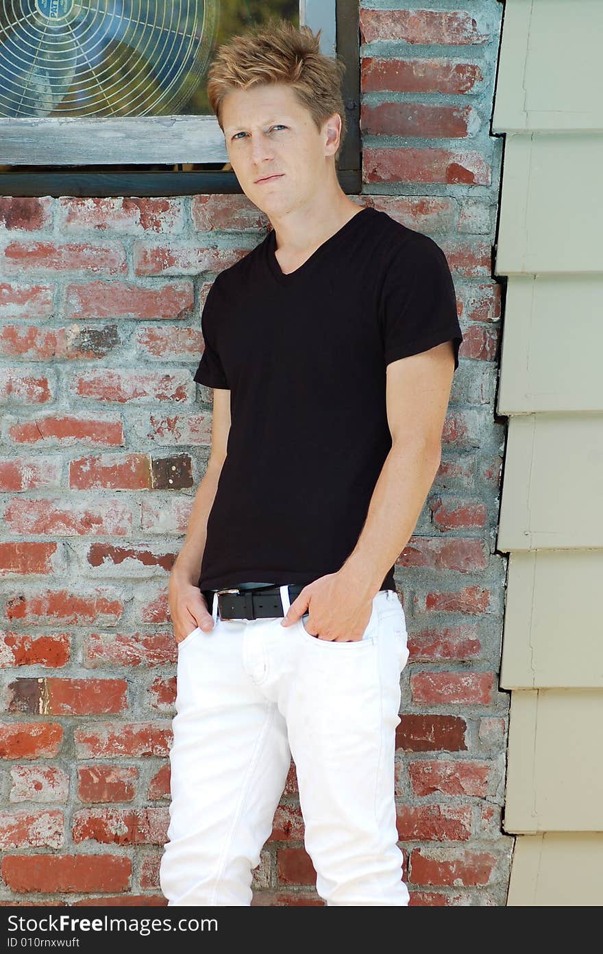 Blond male model standing against a brick wall. Blond male model standing against a brick wall