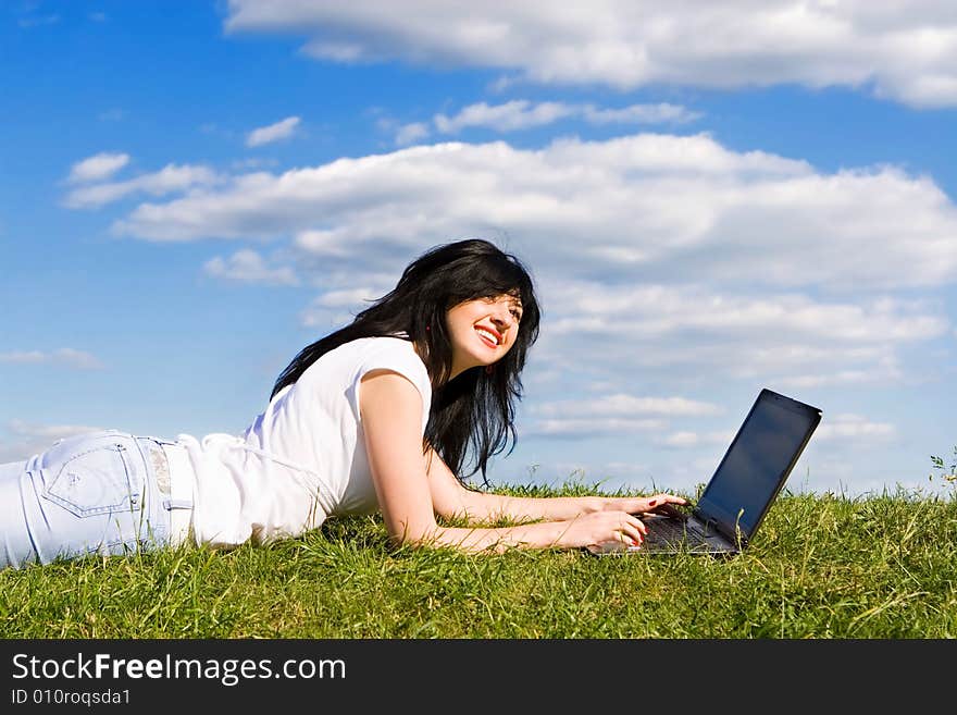 Pretty woman with laptop on the green grass