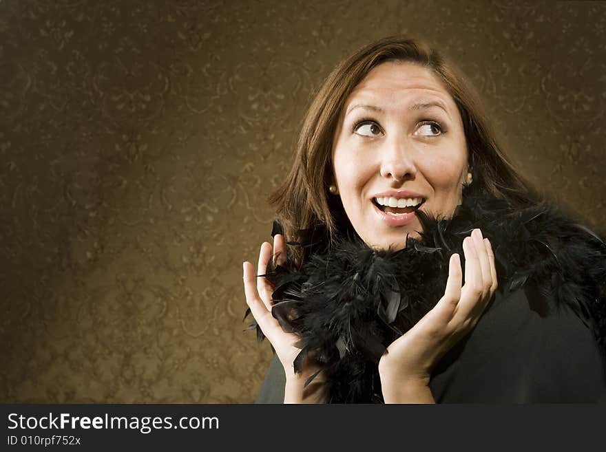 Pretty Hispanic Woman Wearing a Feather Boa in front of Gold Wallpaper. Pretty Hispanic Woman Wearing a Feather Boa in front of Gold Wallpaper