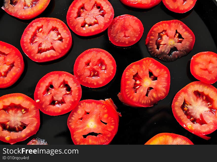 Sliced tomatoes composition on a dark desk