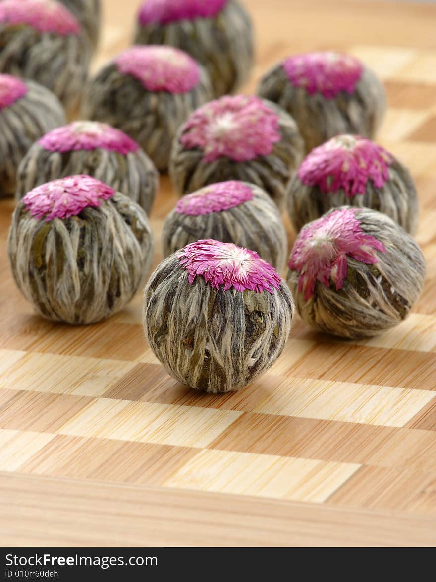 Several handsewn balls of flowering tea ion a bamboo counter. Several handsewn balls of flowering tea ion a bamboo counter.