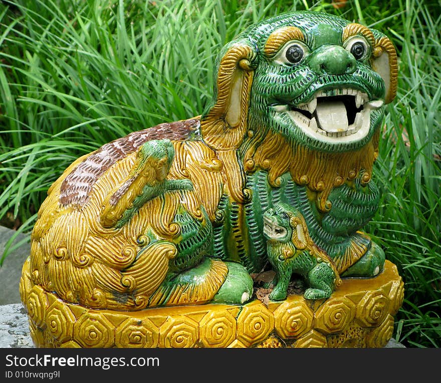 Close-up of pottery lion or dog in deep grass in garden. Close-up of pottery lion or dog in deep grass in garden