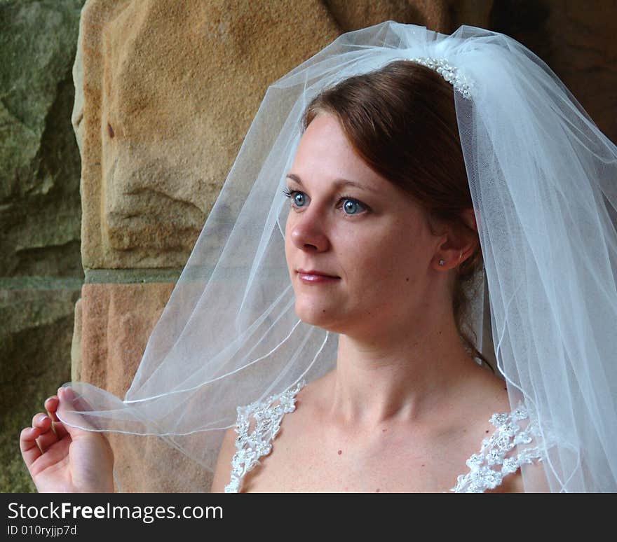 Closeup of bride looking out of stone window. Closeup of bride looking out of stone window