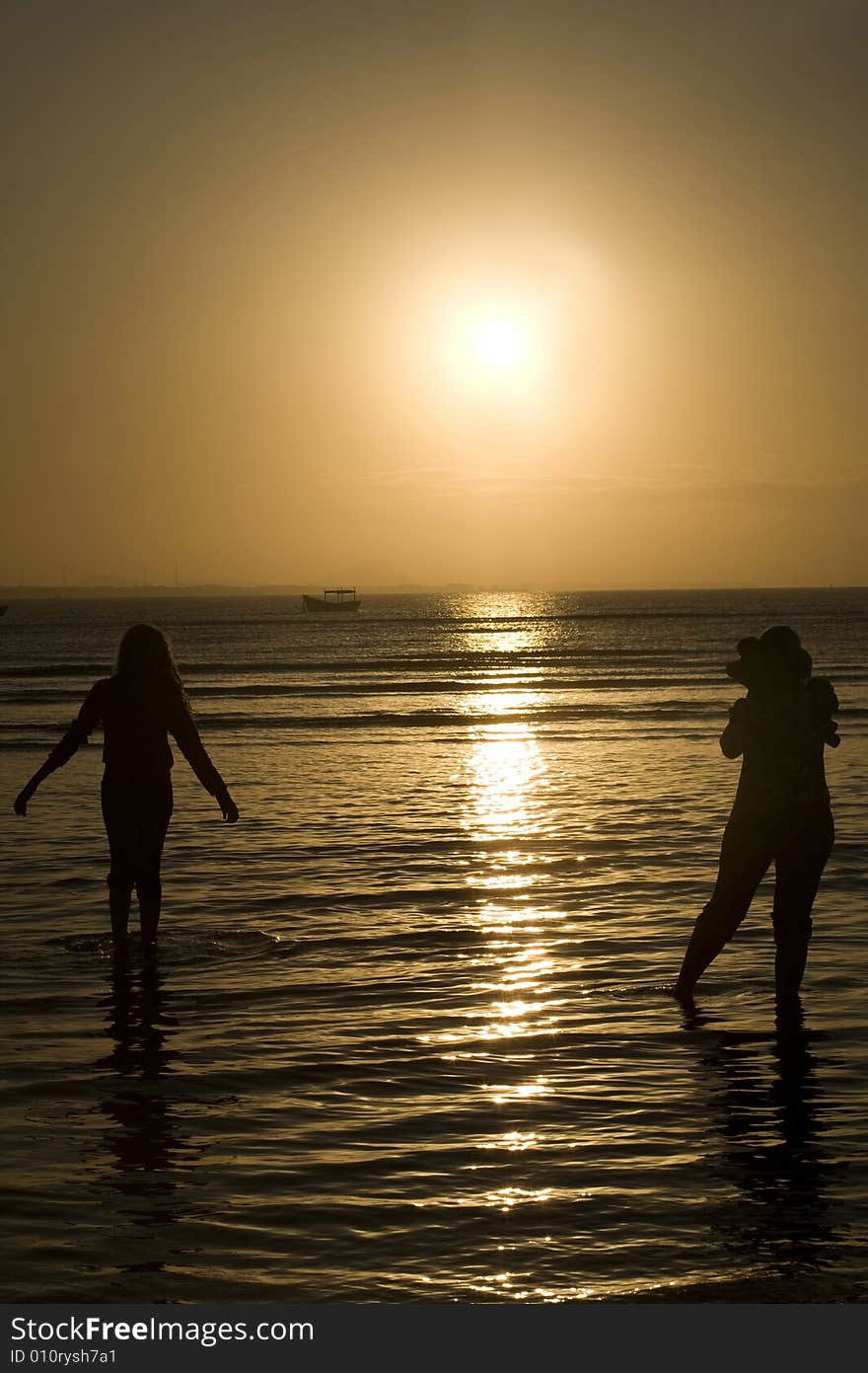 A silhouette of two people in the water. A silhouette of two people in the water