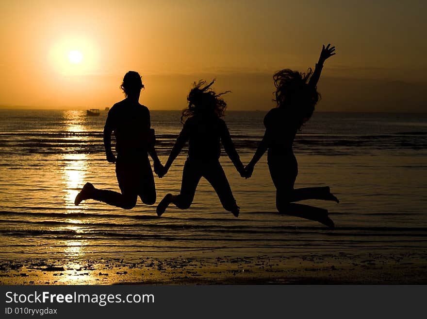 A silhouette of girls jumping in water.