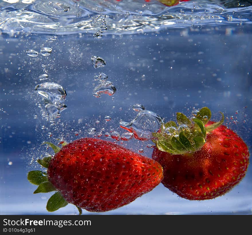 Pair of strawberries splashing into water. Pair of strawberries splashing into water