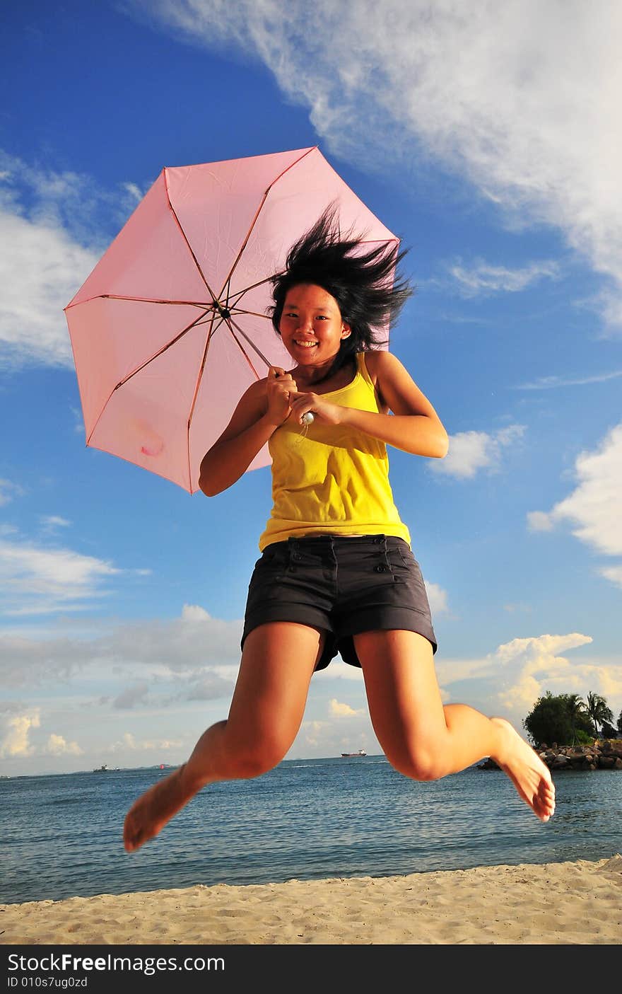 Jumping, smiling girl on the beach with an umbrella. Jumping, smiling girl on the beach with an umbrella.