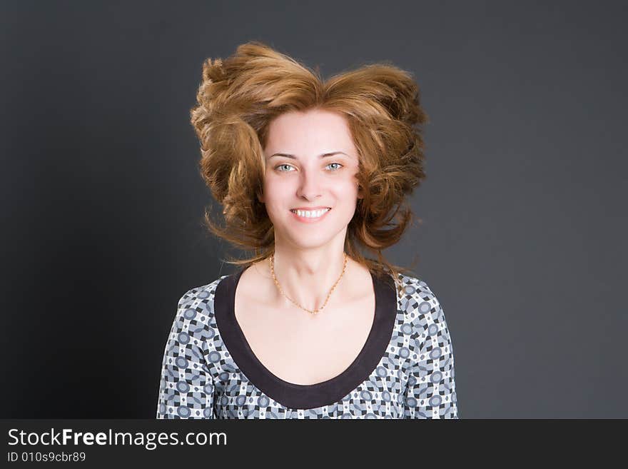 Portrait of the beautiful smiling girl with fluttering hair on a dark background. Portrait of the beautiful smiling girl with fluttering hair on a dark background