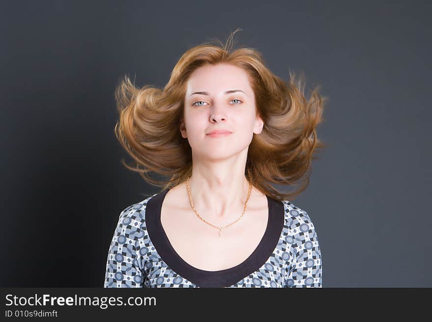 Portrait of the beautiful smiling girl with fluttering hair on a dark background. Portrait of the beautiful smiling girl with fluttering hair on a dark background