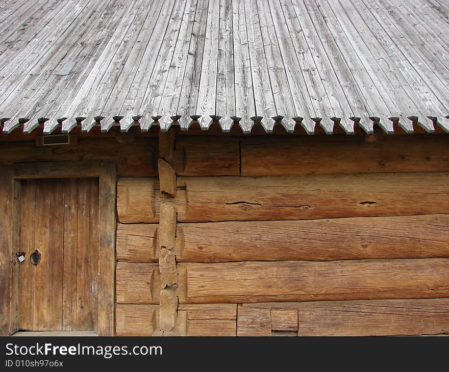 Greater rural log hut from round brown logs, with a roof and a door