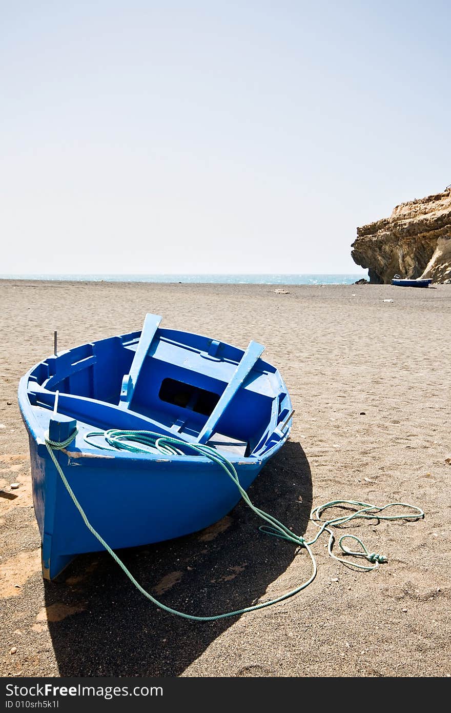 A blue boat on the beach.