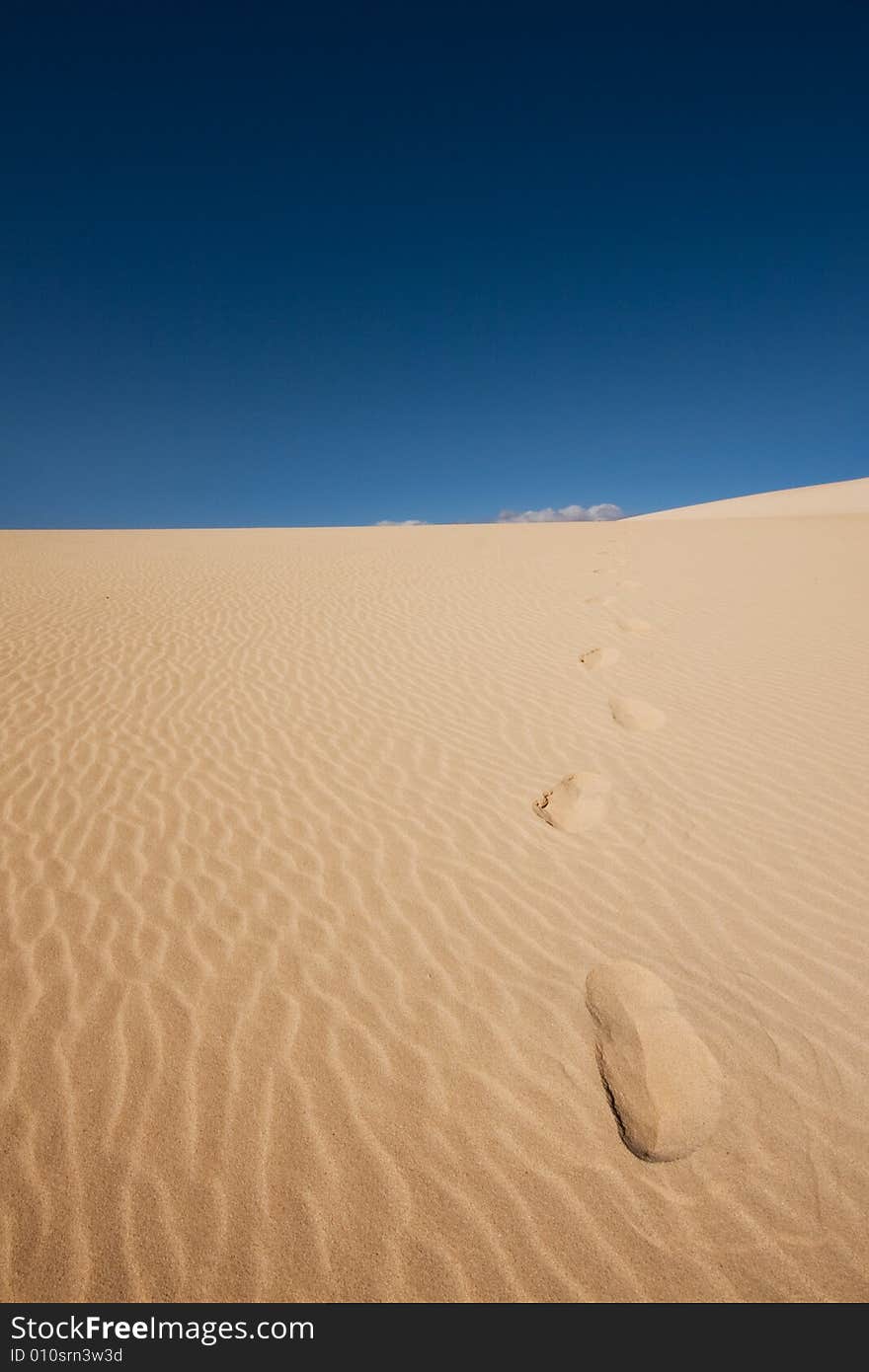 Footsteps in the dunes under a blue sky. Footsteps in the dunes under a blue sky.