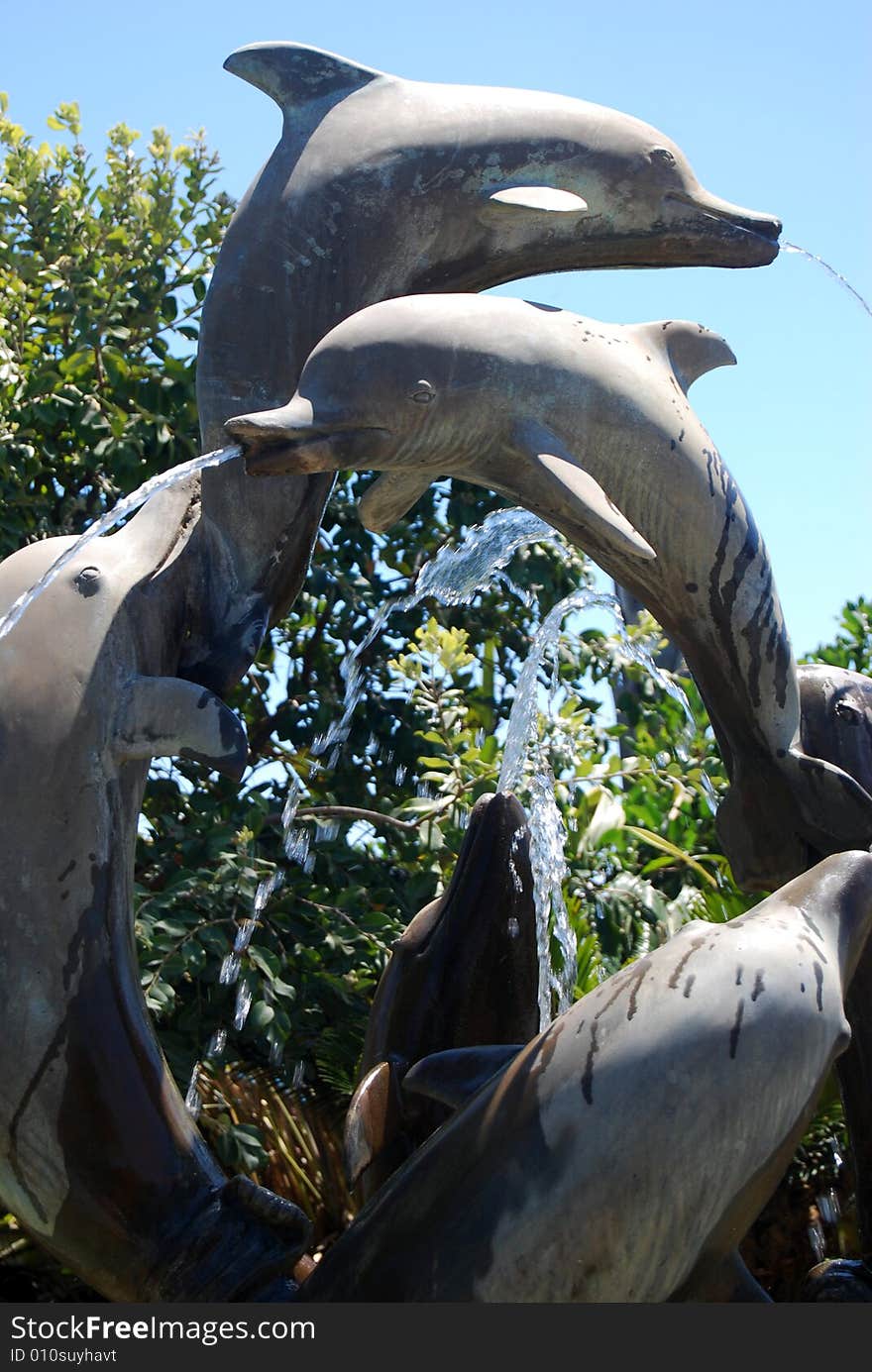 A statue in a fountain with dolphins and jets of water