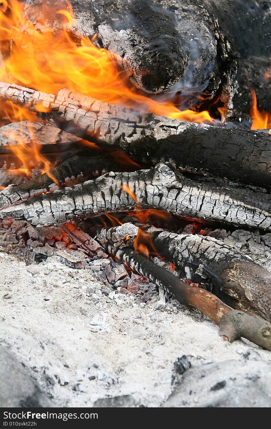 Fireplace with burning fire within. Ash and glowing embers.