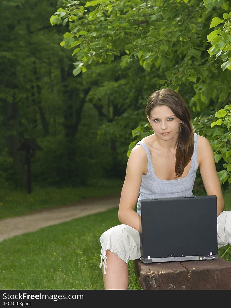 Young business woman relaxing, working on laptop computer on meadow.