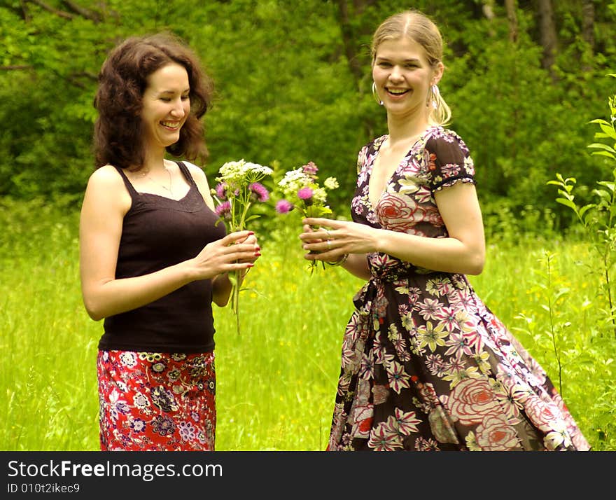 Two women pick up flowers. Two women pick up flowers