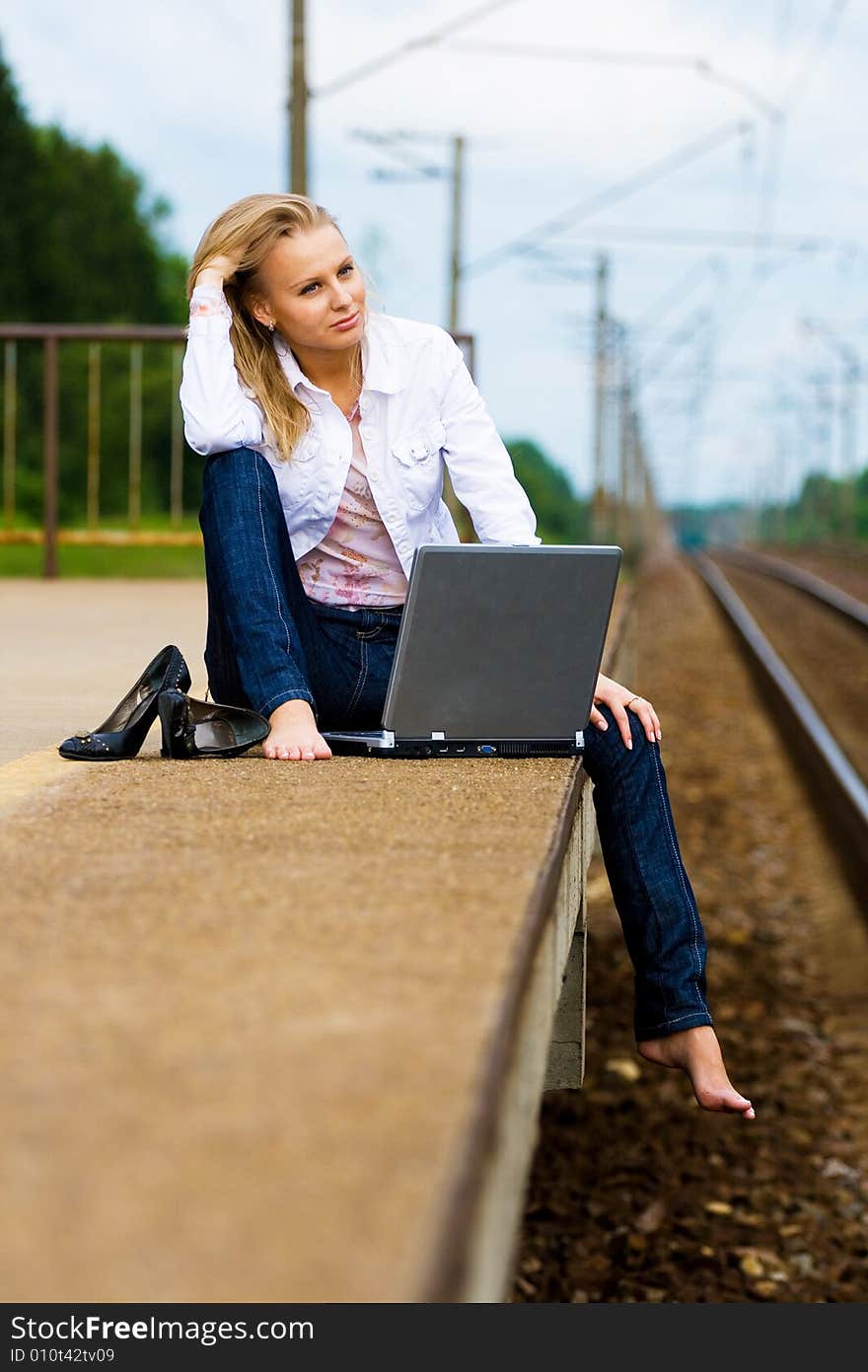 Beautiful young lady with notebook waiting for a train