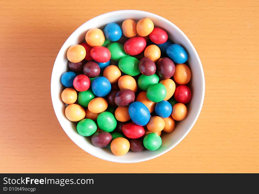 Bowl full of colorful candy on wooden background. Bowl full of colorful candy on wooden background