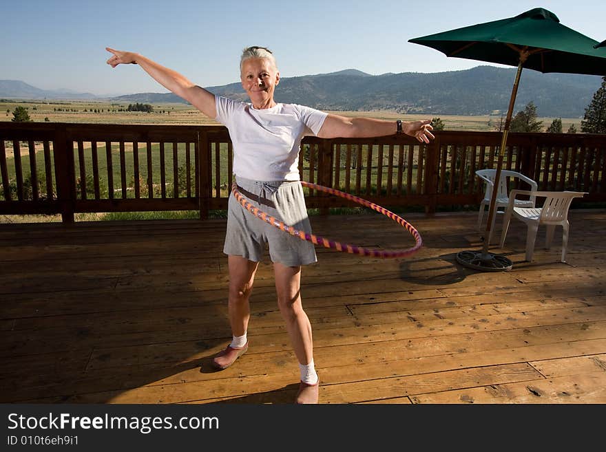 Senior woman hoola hooping on wooden deck with view