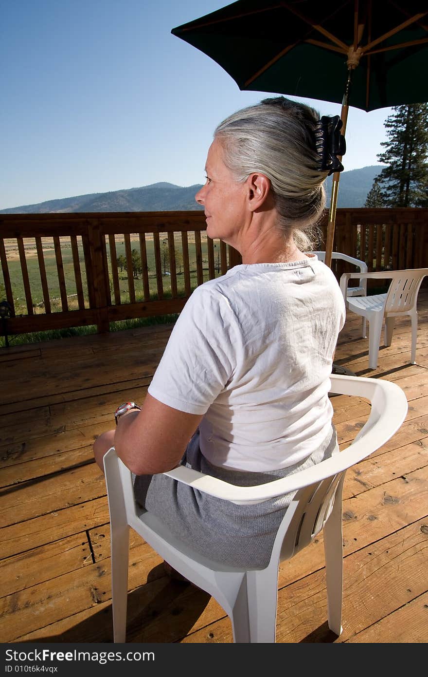 Senior woman sitting on deck admiring view. Senior woman sitting on deck admiring view