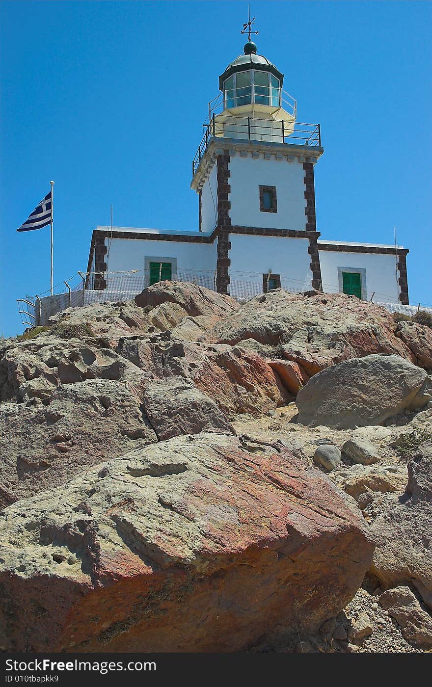 A lighthouse on the rocks on the sunny island of Santorini