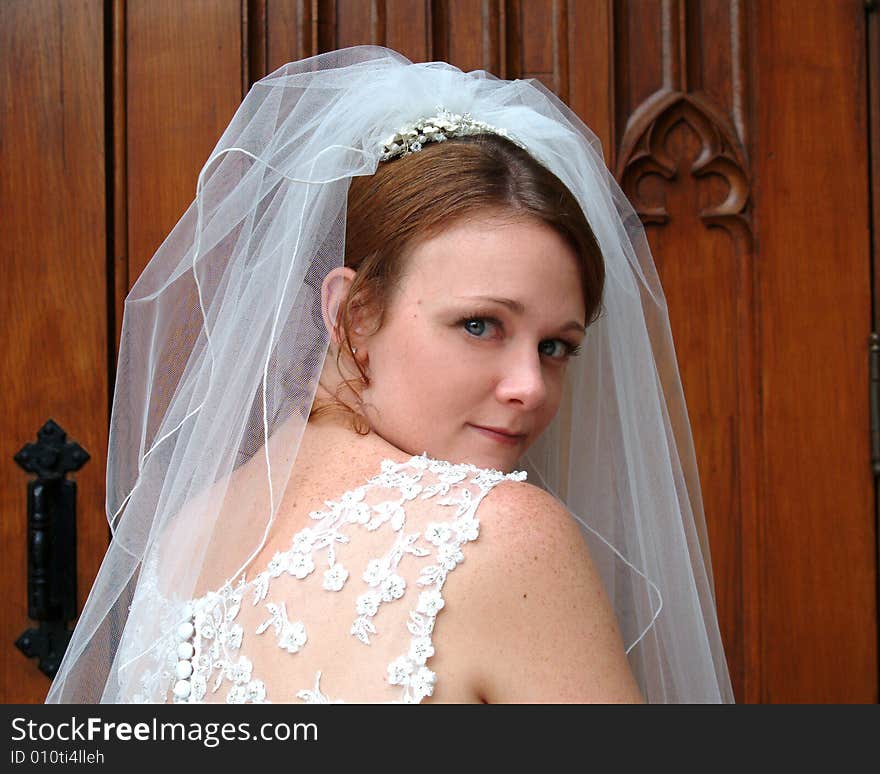 Closeup of bride, walking into wooden doors of church, looking over shoulder. Closeup of bride, walking into wooden doors of church, looking over shoulder