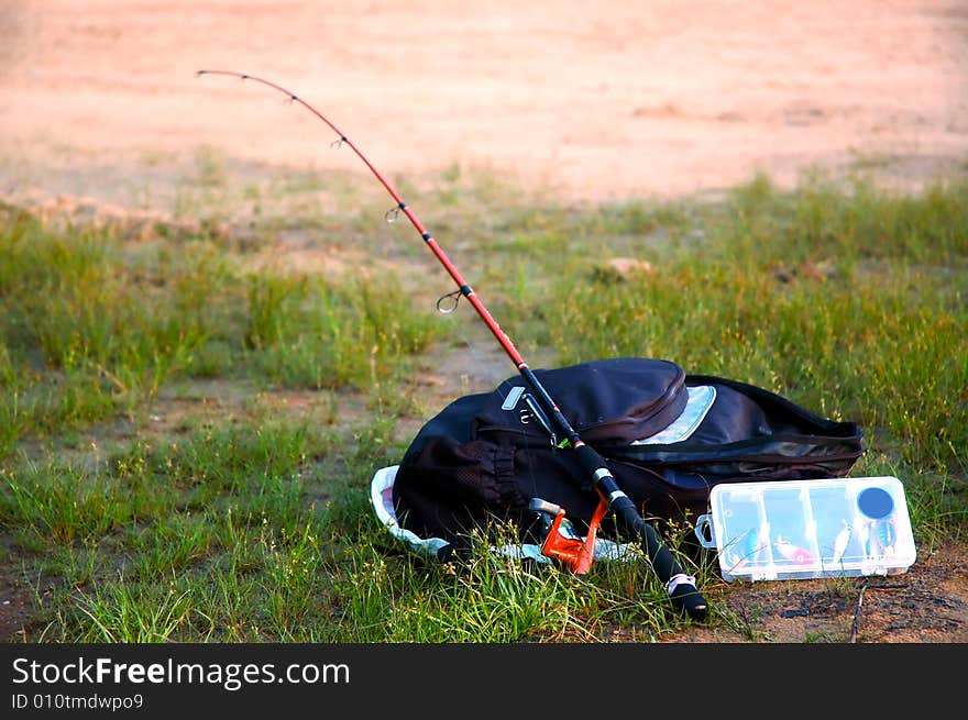 Fishing gears laid down on a wet grass near a pond. Fishing gears laid down on a wet grass near a pond