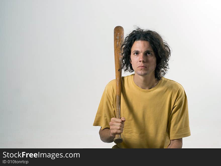 A man holding a  baseball bat and sitting on the floor with a serious look on his face. Horizontally framed photograph. A man holding a  baseball bat and sitting on the floor with a serious look on his face. Horizontally framed photograph