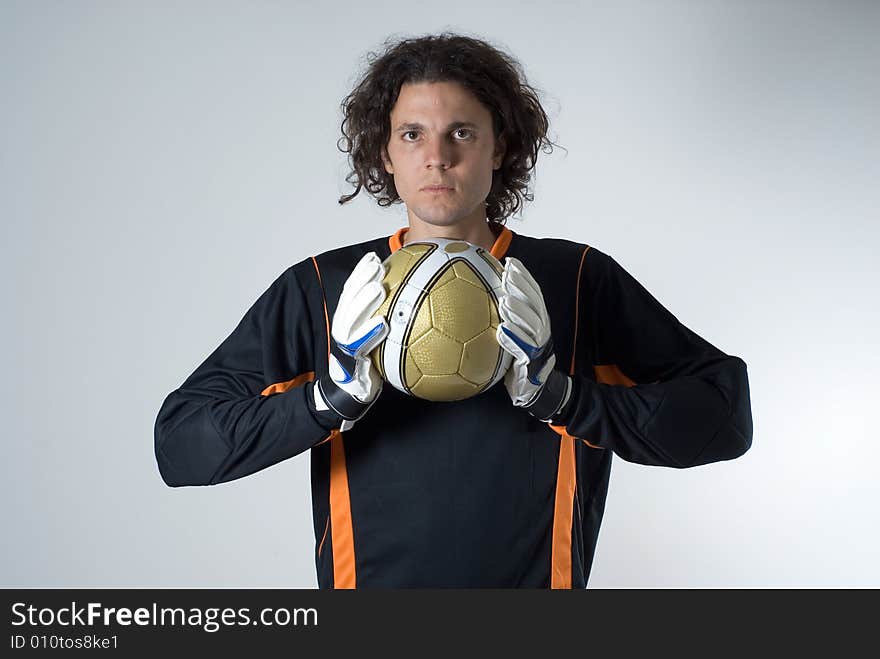 Soccer goalie holds a soccer ball with his goalie gloves and has a serious expression on his face. Horizontally framed photograph. Soccer goalie holds a soccer ball with his goalie gloves and has a serious expression on his face. Horizontally framed photograph