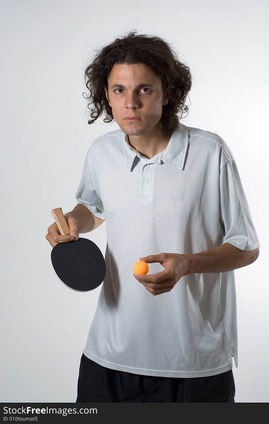 Man standing up holding a ping pong ball and a paddle. He has a serious expression on his face. Vertically framed photograph. Man standing up holding a ping pong ball and a paddle. He has a serious expression on his face. Vertically framed photograph